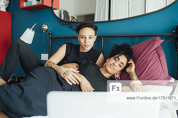 Lesbian couple looking at laptop in bedroom