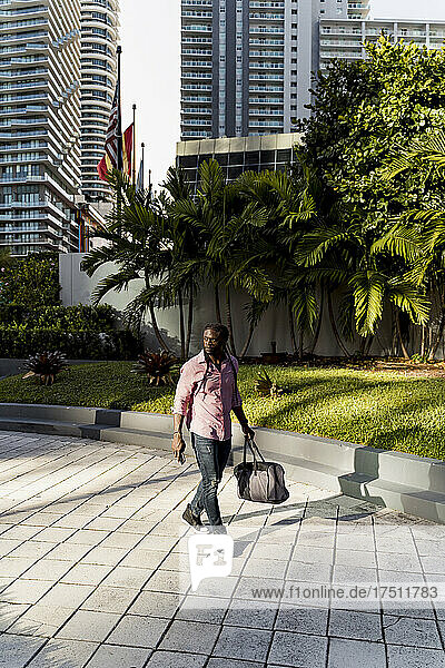 Afro young man with bag walking on footpath in Miami city  Florida  USA