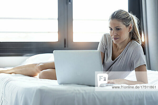 Blond woman using laptop at home
