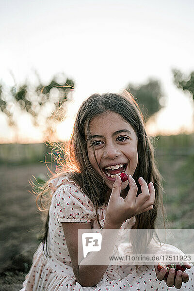 Happy girl eating strawberry in farm