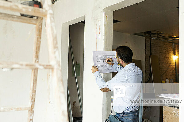 Architect working on plan in a house under construction