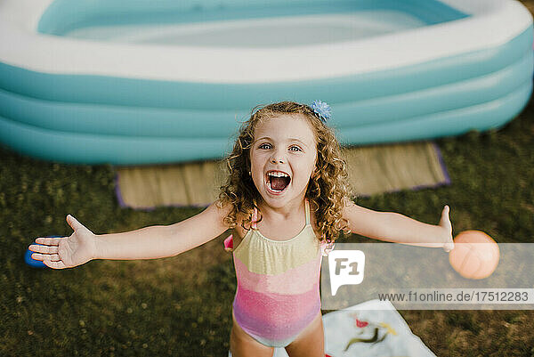 Portrait of a happy girl at inflatable swimming pool in garden