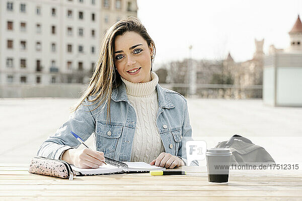 Smiling woman studying at table in university campus
