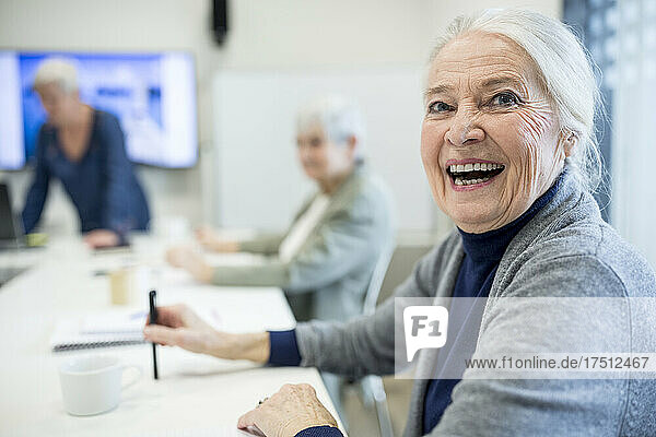 Glückliche ältere Frau  die an einem Seniorenbildungskurs teilnimmt