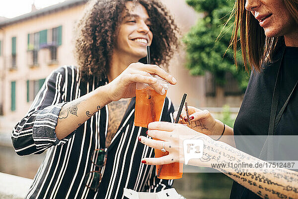 Close-up of happy couple toasting drinks while having fun in city