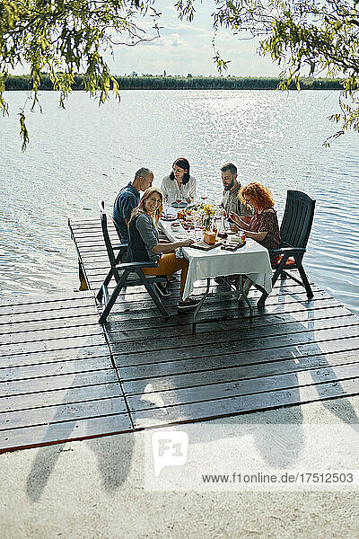 Freunde essen am Steg an einem See zu Abend