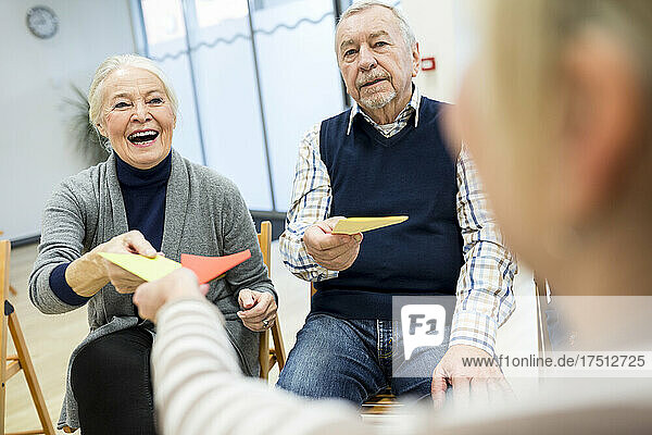 Senioren im Altersheim nehmen an einer Gruppentherapie mit bunten Papierkarten teil
