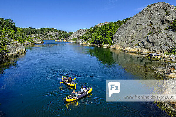 People kayaking across rocky inlet in summer