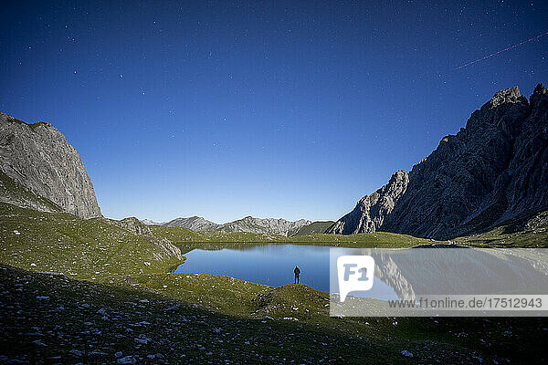 Hiker standing at Lake Kogelsee by night  Tyrol  Austria