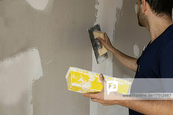 Bauarbeiter verputzt Wand in einem Haus