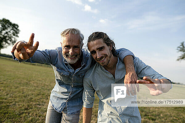 Porträt eines glücklichen Vaters mit erwachsenem Sohn auf einer Wiese auf dem Land