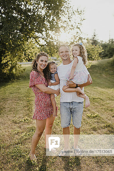Portrait of happy parents with two daughters standing on a meadow