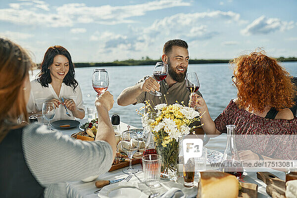 Friends having dinner at a lake rasing wine glasses
