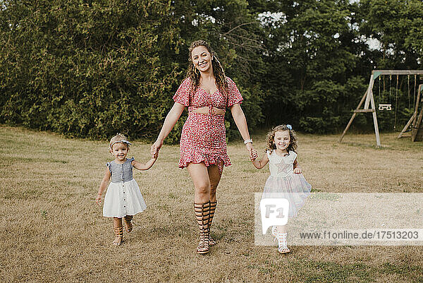 Happy mother walking hand in hand with daughters on a meadow
