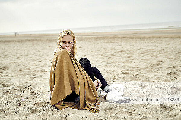 Netherlands  portrait of blond young woman sitting on the beach