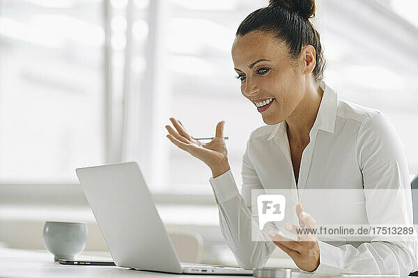 Smiling female entrepreneur using laptop on desk in home office