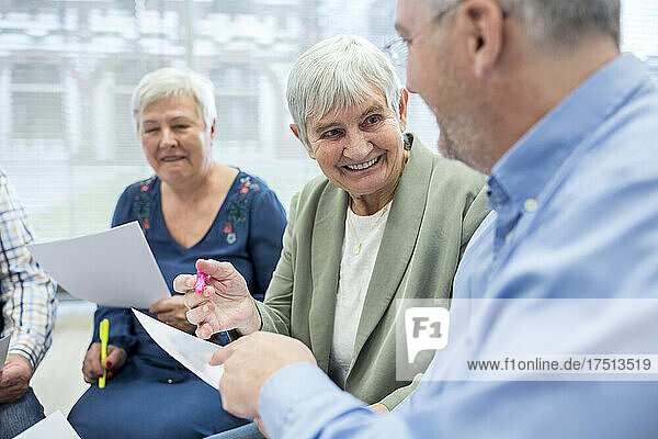 Senioren in der Therapiegruppe im Altersheim schreiben Notizen auf Papierbögen