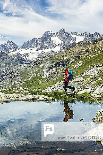 Man walking by lake with reflection at Western Rhaetian Alps Sondrio  Italy