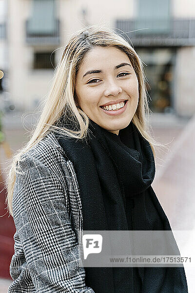 Young smiling woman looking at camera in city
