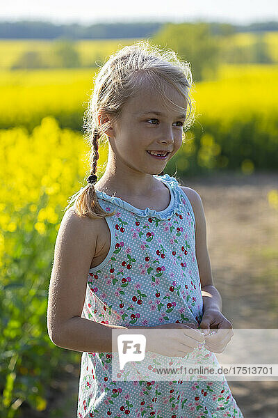Cute little girl standing in farm of rapeseed field
