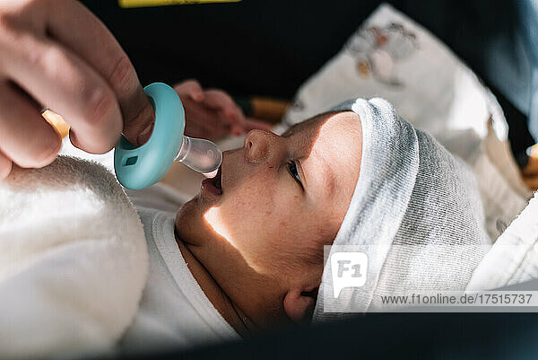 Mother's hand putting pacifier to her newborn baby.