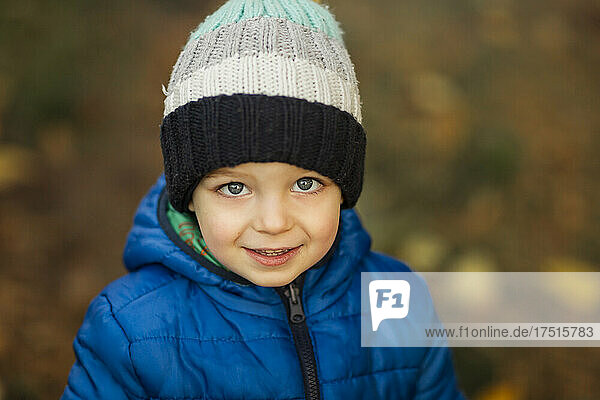 Portrait of small boy with blue eyes in winter hat and blue jack