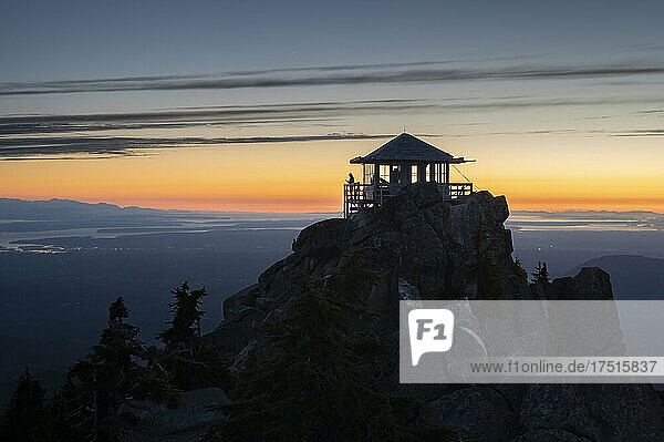 Silhouette of a woman on a fire lookout at sunset