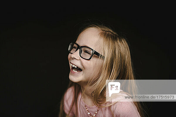 Portrait of a little girl laughing in front of black background