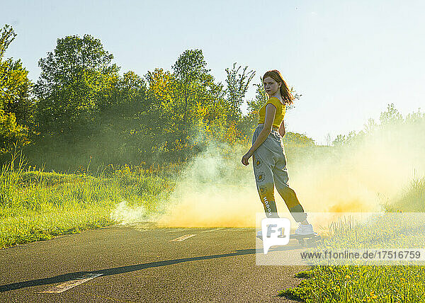 Cool tween girl ripsticking with yellow smokebomb.