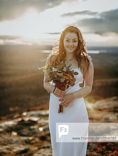 bride with flowers at sunset smiles and grins with happiness
