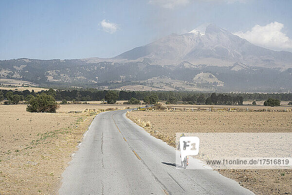 One man riding his bike on a lonely road towards Pico de Orizaba
