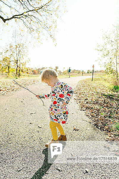 Side view of a toddler dancing in the middle of a walking path