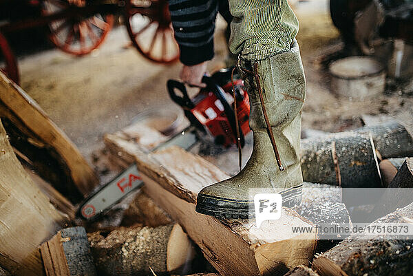 Close-up of a man's working boots. Cutting firewood with a chain