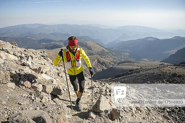 One man wearing yellow using poles climbs up to Pico de Orizaba