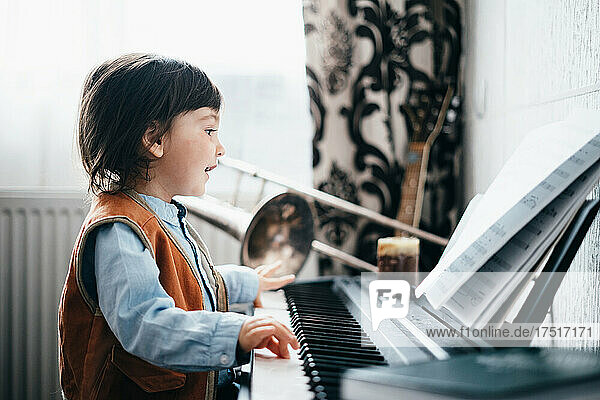 Side view of a happy child playing the piano
