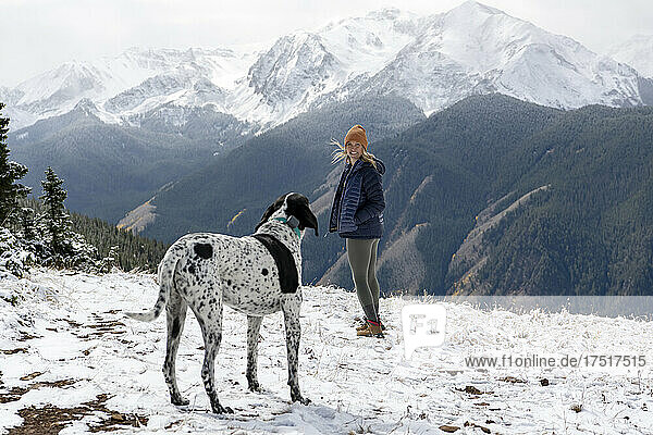Woman hiking with dog on snow covered mountain during vacation