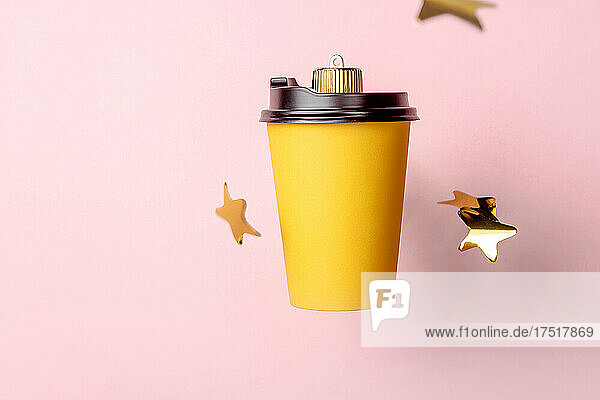 Christmas bauble decoration of coffe cup on pink with stars.