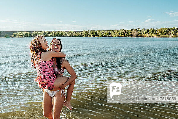 Sisters playing in shallow lake on sunny day