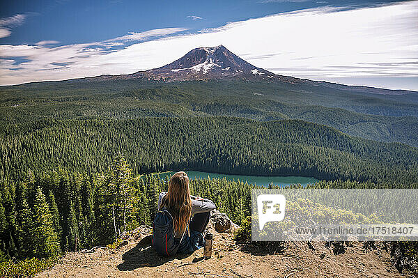 Female sitting on cliff with Mount Adams in the background