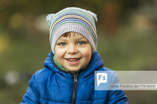 Little boy with blue eyes and blue jacket laughing outdoor