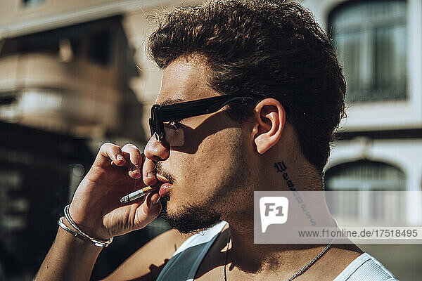 Close-up of a tattooed guy with sunglasses smoking