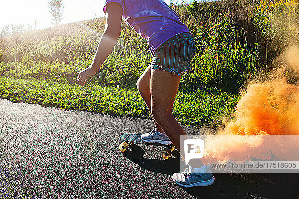 Happy tween girl skateboarding with smokebomb.