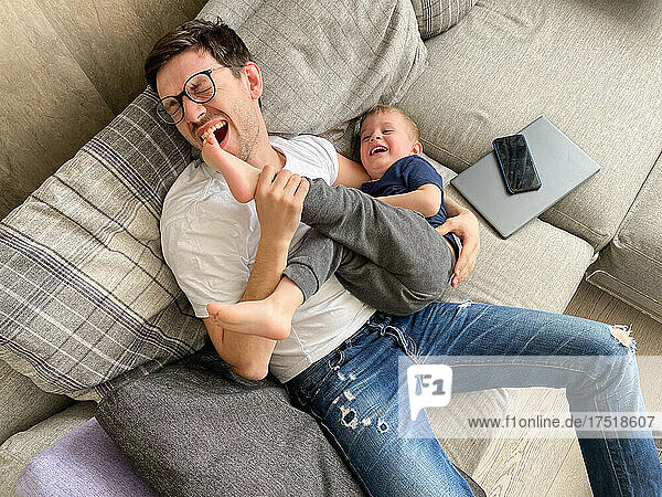 Father making fun with his son while resting from gadget