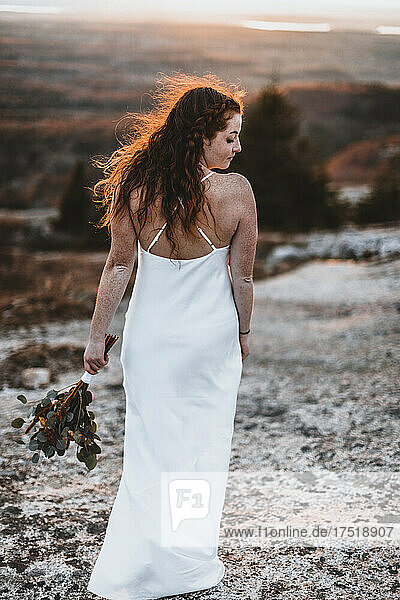 Fire red sunset catches brides wind blown hair with wedding dress