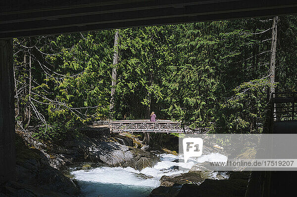 Person standing on a bridge over a rushing river