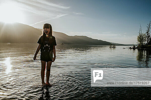 Happy young girl playing in lake on sunny day