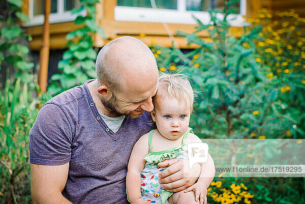 father holds daughter in his arms in the garden