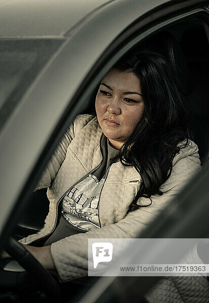 Beautiful plus size asian girl is sitting in the car