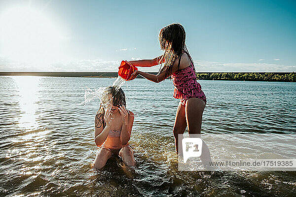 Young girl throwing water on her sisters head