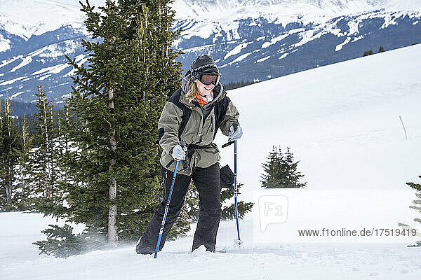 Woman smiles while snowshoeing in mountains